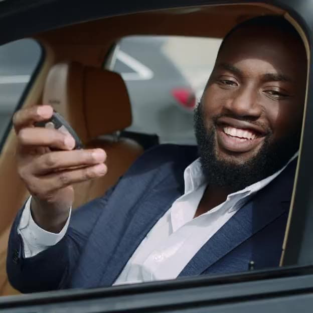 A smiling driver holding up the keys to his car
